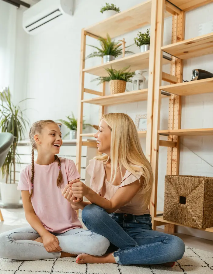 Maman et sa fille partageant un moment de complicité dans un intérieur sain et frais grâce à un entretien régulier de leur climatisation.