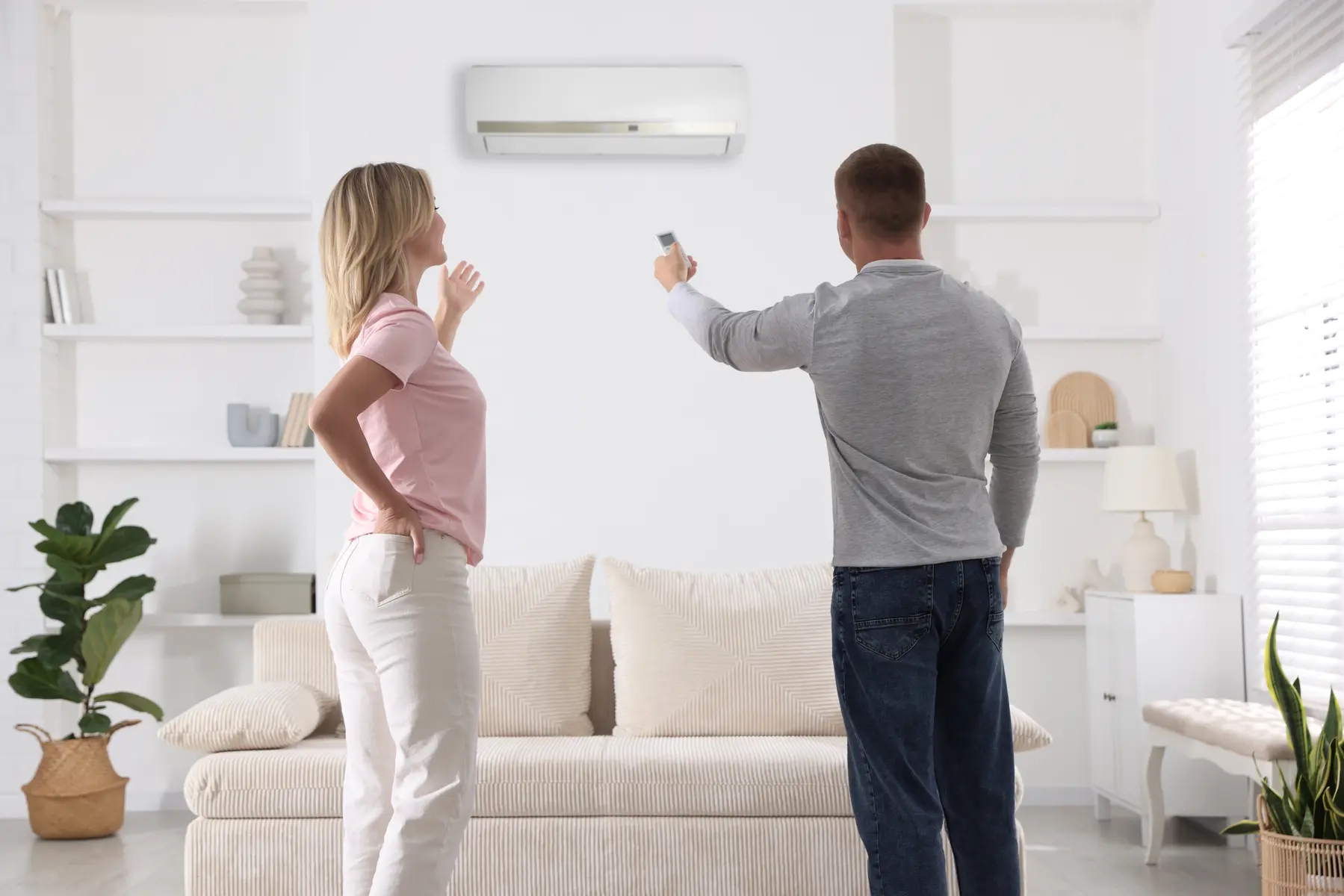 Couple satisfait testant sa nouvelle climatisation murale blanche à La Londe-les-Maures après une pose soignée.